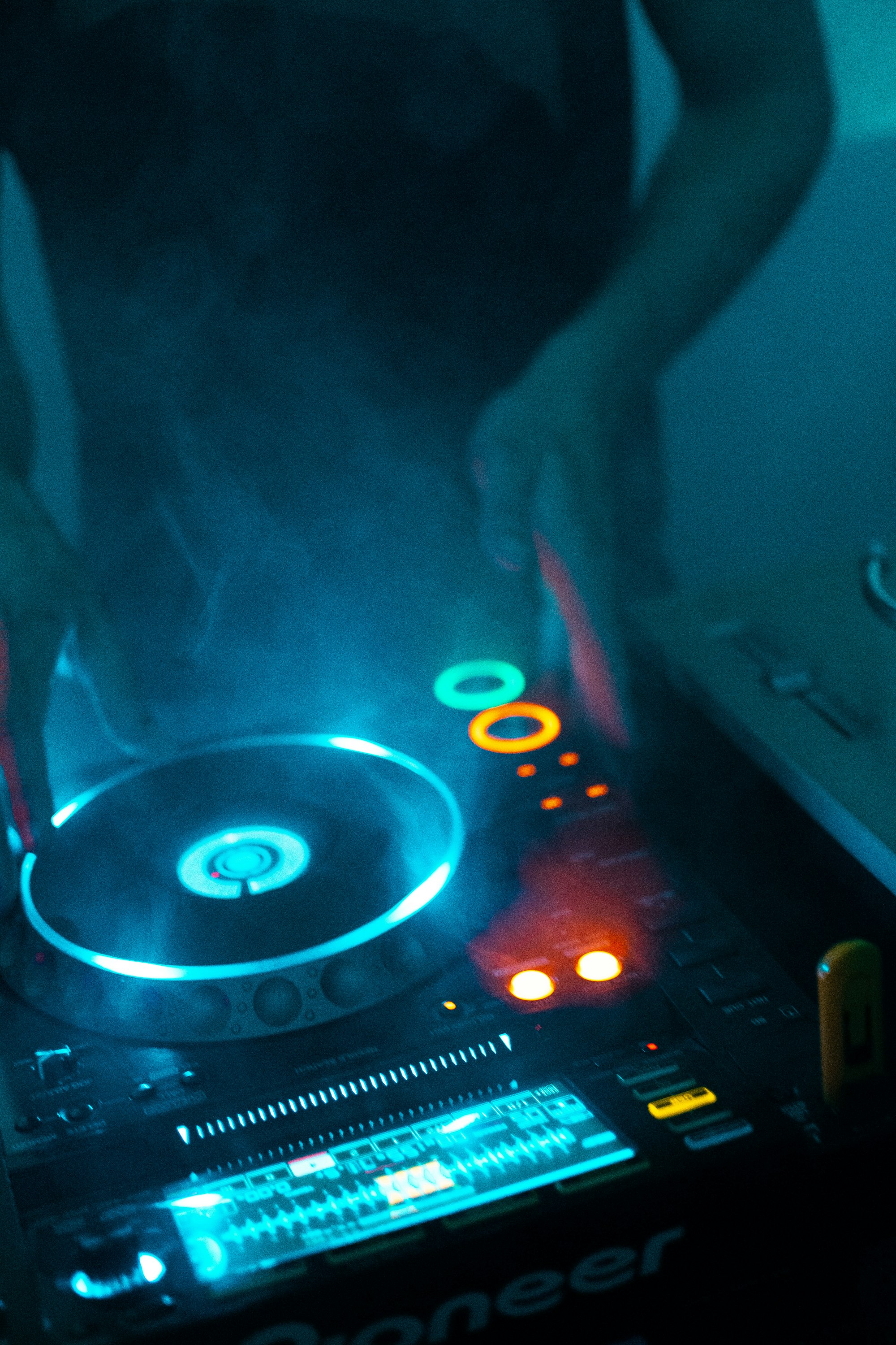 DJ za mixážním pultem, světla a kouř na klubové akci